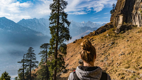 Rear view of woman standing on mountain against sky