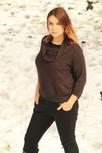 Portrait of woman with hands in pockets standing at beach