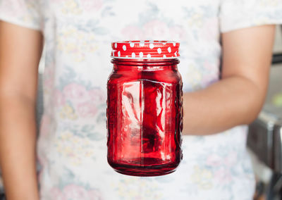 Midsection of person holding red mason jar