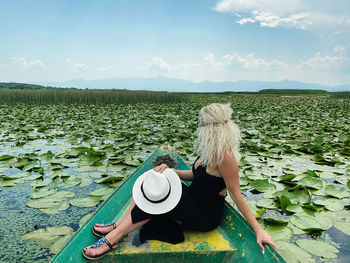 Woman wearing hat against plants against sky