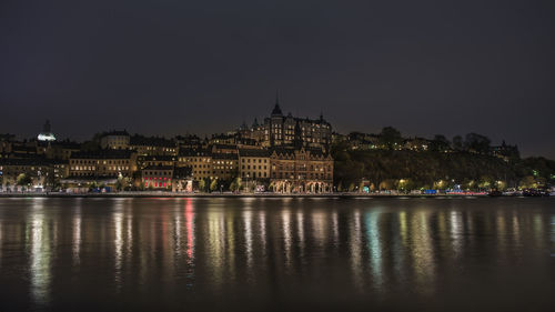 Cityscape by riddarfjarden against sky at night