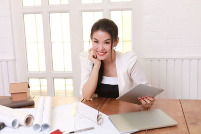 Portrait of young woman using phone on table