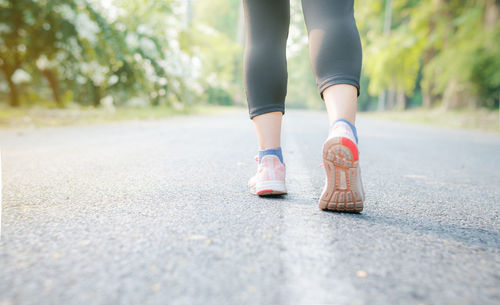 Low section of woman walking on road