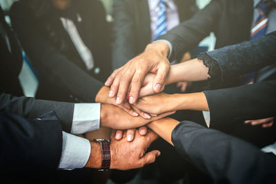 Midsection of colleagues stacking hands