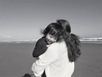 Rear view of woman standing at beach against sky