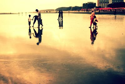 People on beach against sky during sunset