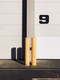 Yellow bollard against white wall