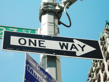 Low angle view of road sign against blue sky