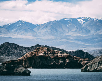 Scenic view of sea by snowcapped mountains against sky