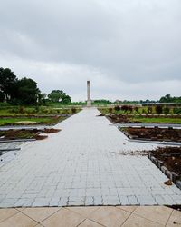 Footpath leading towards city against sky