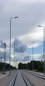 Street by railroad tracks against sky