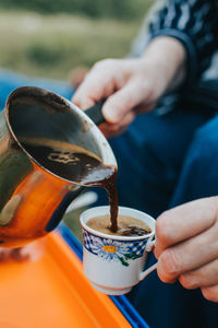 Close-up of hand pouring coffee in cup