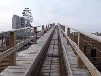 Footbridge in city against sky