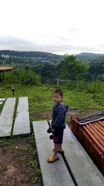 Rear view of boy on plants against sky