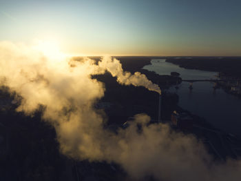 Smoke stacks emitting smoke at sunset