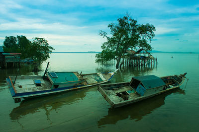 Boats moored in calm lake against blue sky