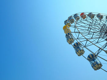 Low angle view of cropped ferries wheel against clear blue sky