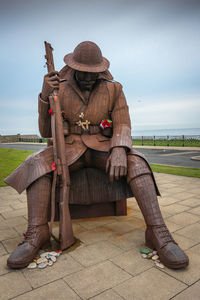 Full length of man sitting on chair at field against sky