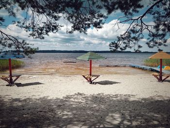 Deck chairs on beach against sky