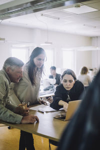 Male and female fashion designers looking at laptop during meeting at workshop