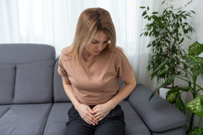 Young woman sitting on sofa at home