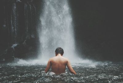 Rear view of shirtless man splashing water fountain