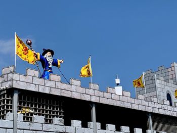 Low angle view of flags against buildings against clear blue sky