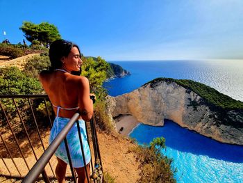 Young woman standing by sea against sky