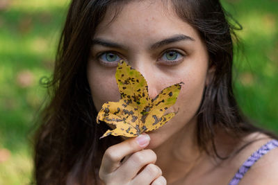 Close-up portrait of woman holding leaf