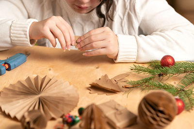 Girl makes christmas tree decorations out of paper with her own hands. step 3