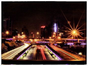 Light trails on road in city against sky at night