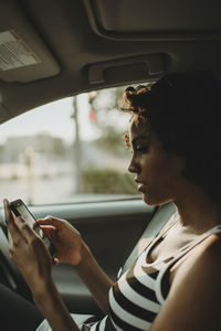 Side view of man using smart phone in car