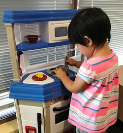 Side view of a girl playing kitchen