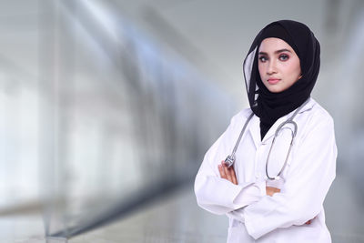 Portrait of female doctor standing against wall