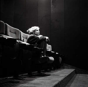 Woman sitting on sofa in darkroom