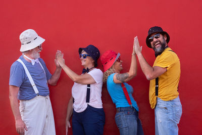 Happy couples giving high-five against red background