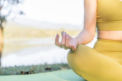 Close up of a woman's hand during her yoga meditation at an outdoor lake park