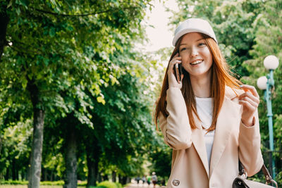 Redhead woman with cell phone outdoor portrait. happy young business woman with cell phone in hand