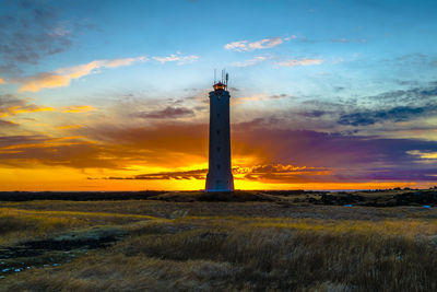 Scenic view of landscape against cloudy sky at sunset