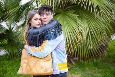 Happy young couple standing against plants