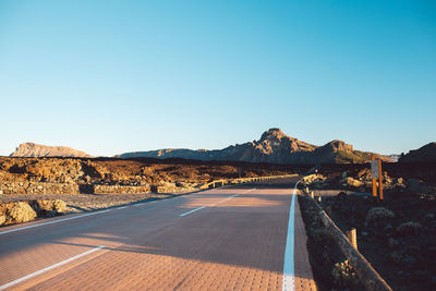 Road by mountain against clear sky