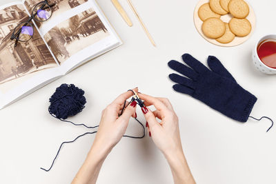 Woman hands knit glove with bamboo spokes from blue wool yarn. 