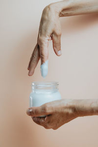 Cropped hand of woman dipping finger in moisturizer