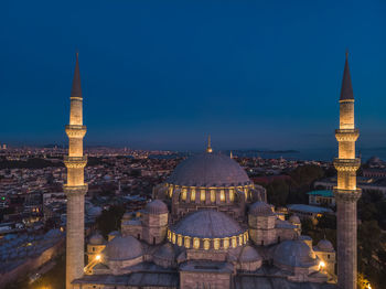 Illuminated buildings in city against clear sky