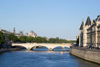 Bridge over river in city against clear sky