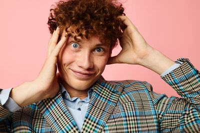 Portrait of man gesturing against pink background