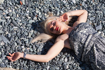 Portrait of young woman lying down on pebbles