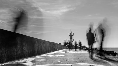 People on pier with lighthouse in perspective