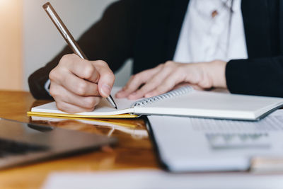 Midsection of man holding paper while sitting on table