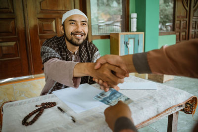 Young man shaking hand with friend at mosque